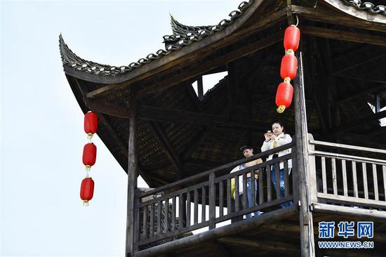  游客在重慶市武隆區(qū)黃鶯鄉(xiāng)復興村的觀景樓上欣賞田園景色（2019年3月28日攝）。 新華社記者 劉潺 攝